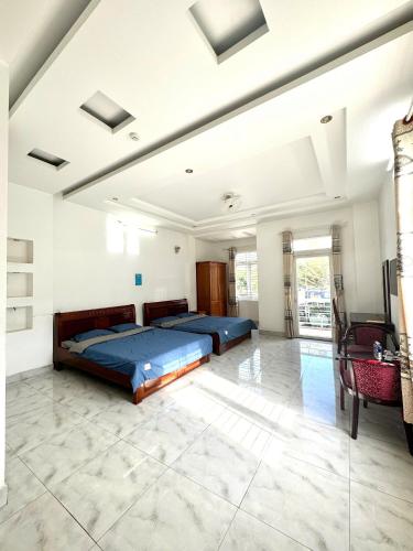 two beds in a large room with white walls at Nhà Nghỉ Hoàng Gia Phát in Buôn Kô Sir