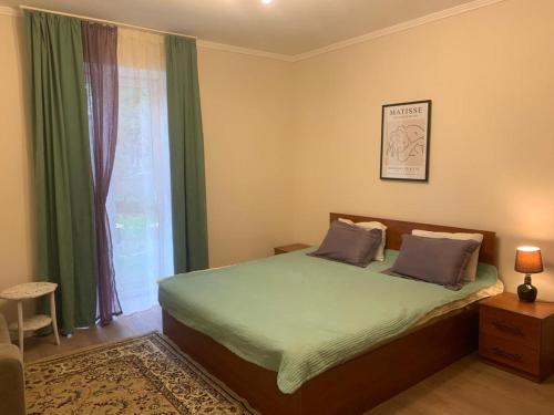 a bedroom with a bed with green sheets and a window at Raduga West Pineforest - коттедж в аренду на Иссык-Куле in Koshkolʼ