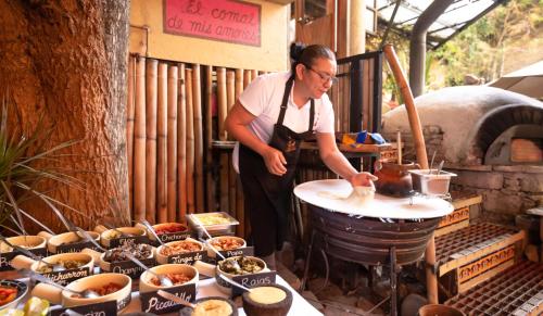 a man in an apron making food on a table at Petit Mesón (Pet Friendly Hotel) in Valle de Bravo