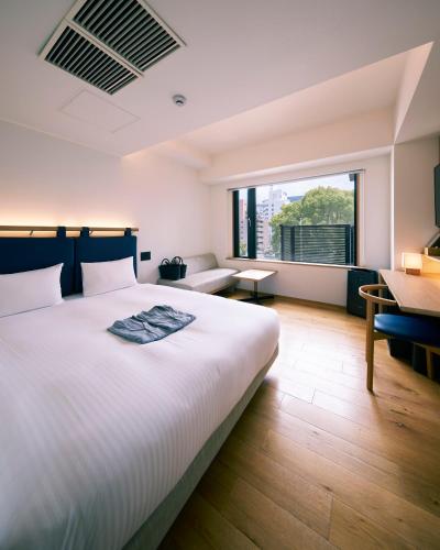 a bedroom with a large white bed and a desk at hotel androoms Kyoto Shichijo in Kyoto
