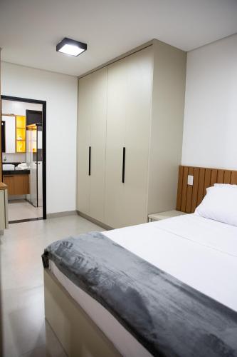 a bedroom with a large bed and white cabinets at Studios Interlagos 201 in Araguari