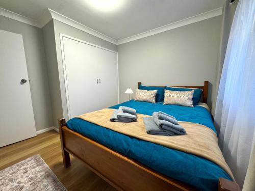 a bedroom with a blue bed with towels on it at The Gem on Britannia in Stanthorpe