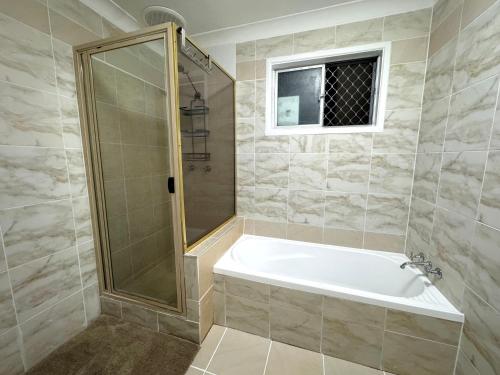 a bathroom with a shower and a white bath tub at The Gem on Britannia in Stanthorpe