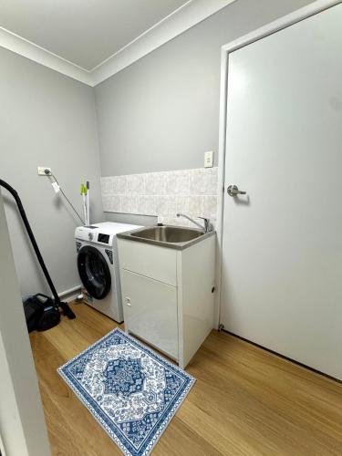 a laundry room with a sink and a washing machine at The Gem on Britannia in Stanthorpe
