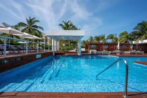 カンクンにある2BR Beach & Marina front Condo w/ Top Featuresのヤシの木が茂るリゾートのプール