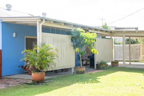 a blue house with potted plants in a yard at Great Escape at Amity in Amity Point