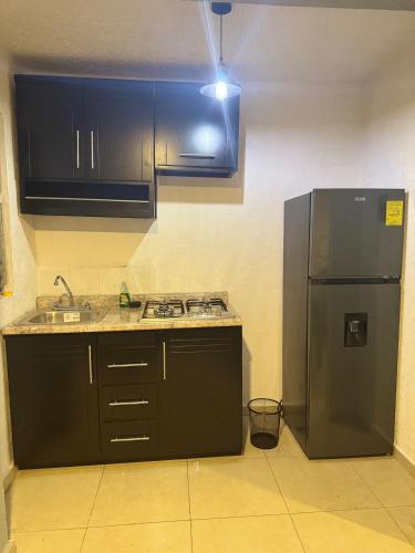 a kitchen with black cabinets and a stainless steel refrigerator at Casa Marquesa 3 Habitaciones in Acapulco
