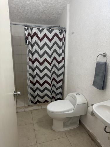 a bathroom with a toilet and a shower curtain at Casa Marquesa 3 Habitaciones in Acapulco