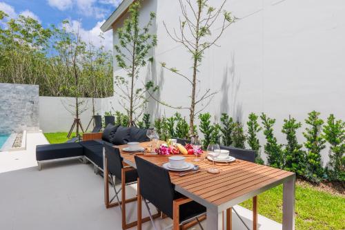 a wooden table and chairs on a patio at Modern 3BR Pool Villa near Laguna- Lux Pride 4 by Warm Plus in Ban Pak Lak