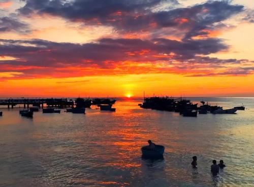 a group of people in the water at sunset at Homestay TIẾN THÀNH in Ninh Hải