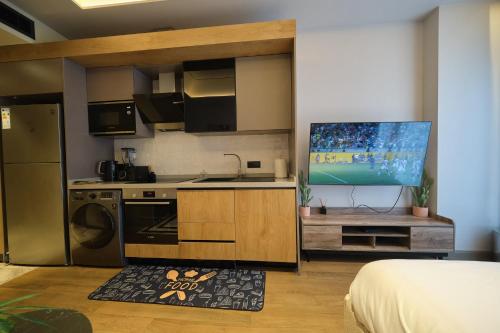 a kitchen with a stove and a tv in a room at The Diamond In City Luxury Suites By ZENORA Living in Accra