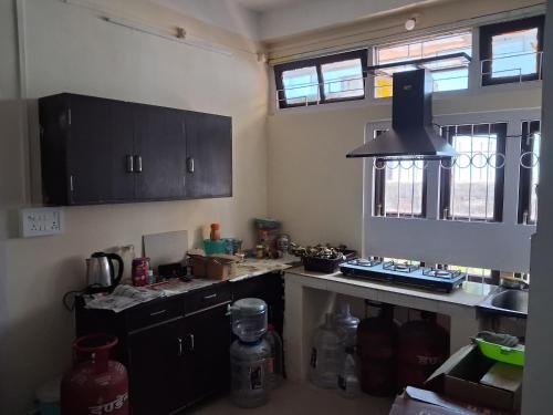 グワーハーティーにあるDorika Homestay, Guwahatiのキッチン(黒いキャビネット、カウンタートップ付)