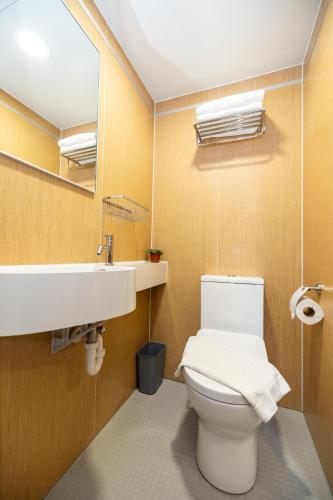 a bathroom with a toilet and a sink and a mirror at mu petite in Ipoh