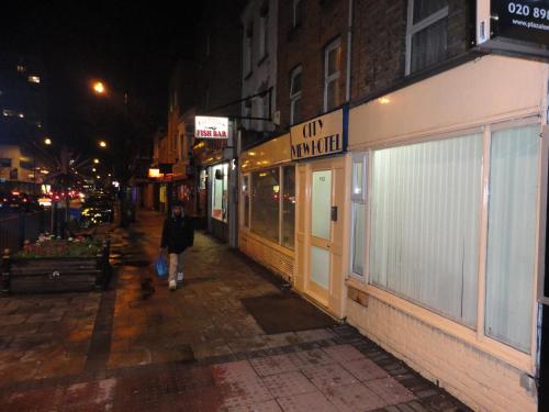 a person walking down a street at night at City View Hotel Roman Road in London