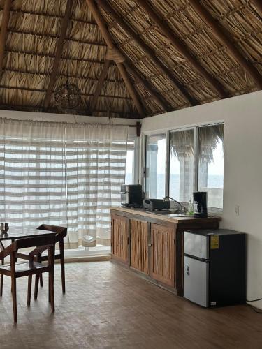 a kitchen with a table and a table and some windows at Papapa grecas in Zipolite