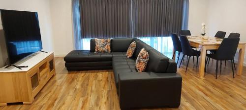 a living room with a black couch and a table at Old Port Townhouse Central to Everything in Echuca