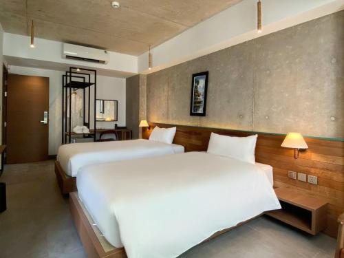two beds in a hotel room with white sheets at CHECK inn Phnom Penh Royal Palace in Phnom Penh