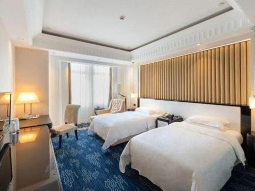 a hotel room with two beds and a desk at Tongxiang Inspirock Hotel in Jiaxing