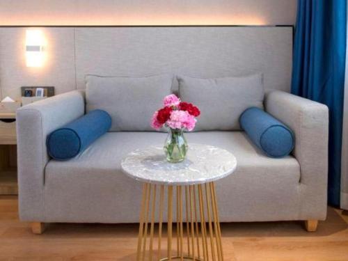 a vase of flowers on a table in front of a couch at danfeng kelly hotel in Shenzhen
