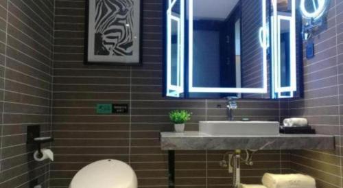 a bathroom with a sink and a toilet and a mirror at Xana Hotelle·Tianshui Shangyi Plaza in Tianshui