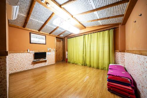 全州市にあるDdlanchae Guesthouse - New Towerの緑のカーテンとソファのある空の部屋