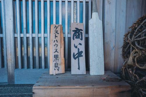 three wooden signs sitting next to a fence at ゲストハウス黒島 in Wajima