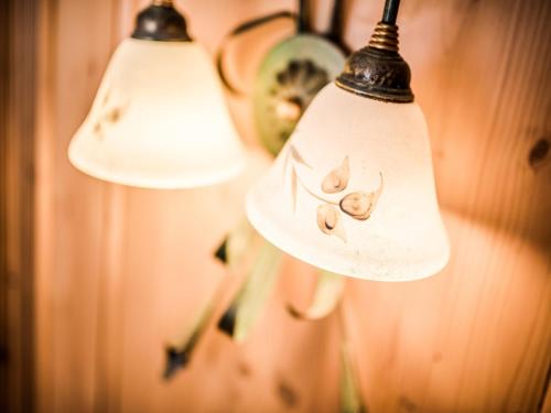 a group of three lights hanging on a wall at Hotel Alpenjuwel in Melago