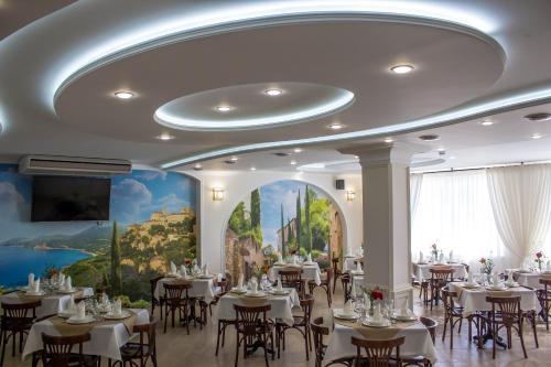 a banquet hall with tables and chairs and a mural at Aristokrat Hotel in Nizhneye Dzhemete