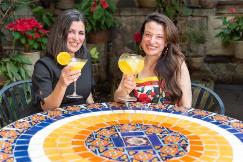 two women sitting at a table with drinks at Mesón De Leyendas Breakfast & Downtown in Valle de Bravo