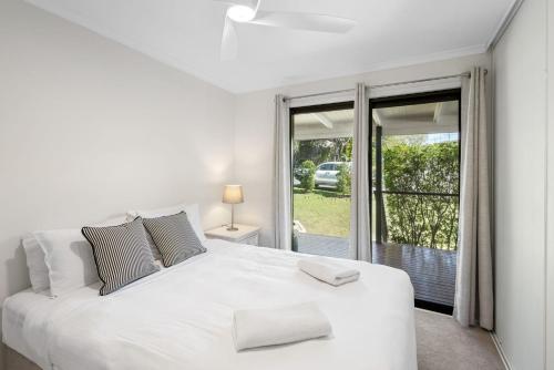 ein weißes Schlafzimmer mit einem großen weißen Bett und einem Fenster in der Unterkunft 26 Gannet Street, Peregian Beach in Peregian Beach