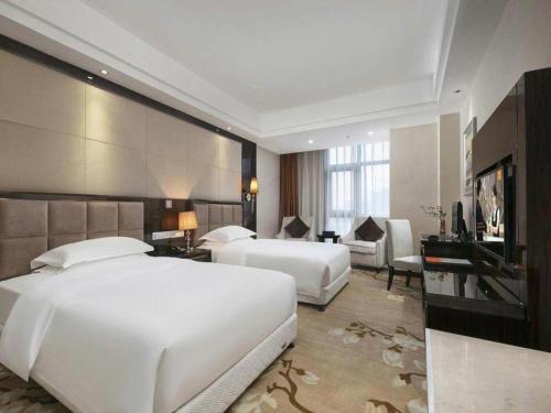 a hotel room with two beds and a television at Vienna Hotel Henan Xinyang East Zone of Central Hospital in Pingqiao
