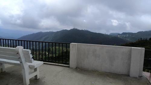 a white bench sitting on a balcony overlooking a mountain at Valley View in Kodaikānāl
