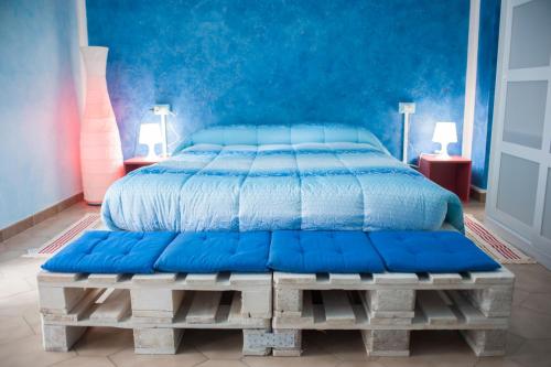 Cama con manta azul sobre una plataforma de madera en B&B Casa Tua, en Castelfrentano
