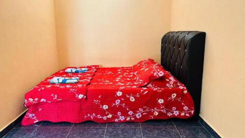 a bed with a red blanket on top of it at Capital O 91191 Chalet Cd Impiana in Kulim