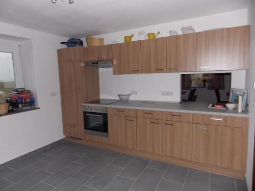 a kitchen with wooden cabinets and a stove at Ferienhaus Hofmann Strüth 3 in Röttingen