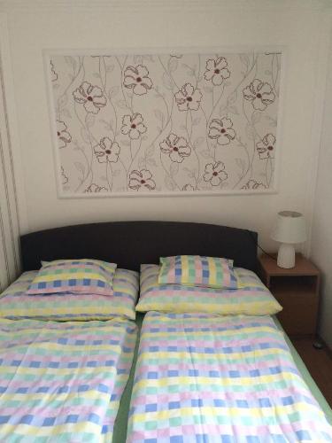 a bed with two pillows and a picture on the wall at Sárgapart Holiday Home in Poroszló