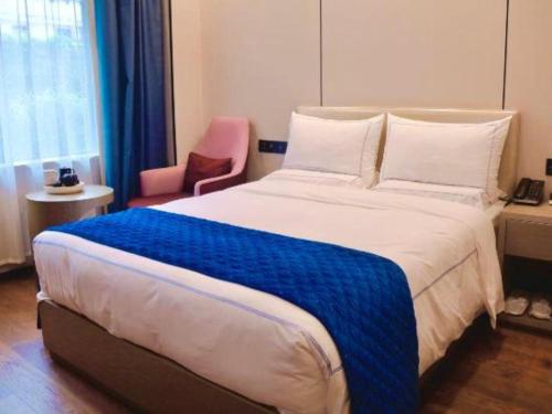 a bedroom with a large bed and a pink chair at Xiamen Seashine Lakeview Hotel in Xiamen