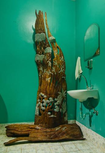 a bathroom with a wooden carving of a tree next to a sink at Deep Forest Garden Hotel in Puerto Princesa City