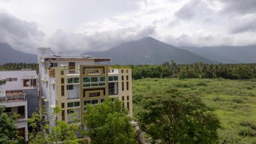 a building in a field with a mountain in the background at Sree Bharat Apartment in Coimbatore