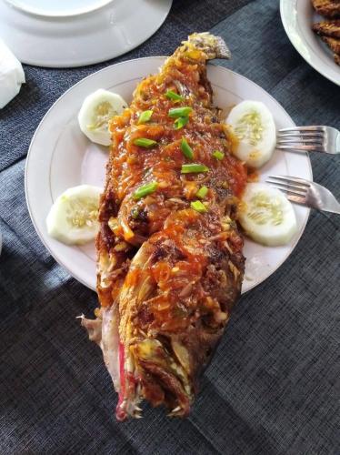 a plate of food with a piece of fish with sauce at Vakantie Vila Wab in Watnil