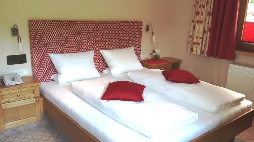 a bed with two red pillows on top of it at Hotel Garni Erler in Mayrhofen