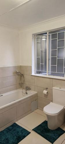 a bathroom with a toilet and a tub and a window at 46 On Aries in Northwold