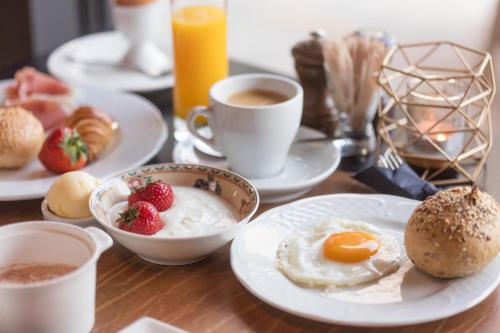 a table with plates of breakfast foods and cups of coffee at Guesthouse Amfora in Poperinge