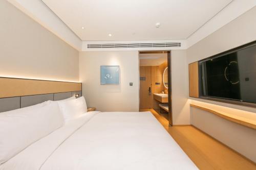 a bedroom with a large white bed and a flat screen tv at JI Hotel Gu'an Daxing International Airport in Dongsunguo