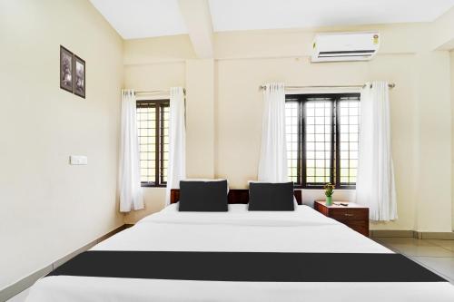 a bedroom with a large bed with two windows at Super Hotel O Ambalamedu in Cochin