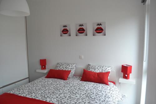 Dormitorio blanco con cama con almohadas rojas en La boîte rouge en Stavelot