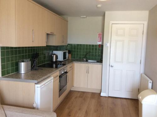 a kitchen with white cabinets and green tiles at Discovery Bay in St Ouen's