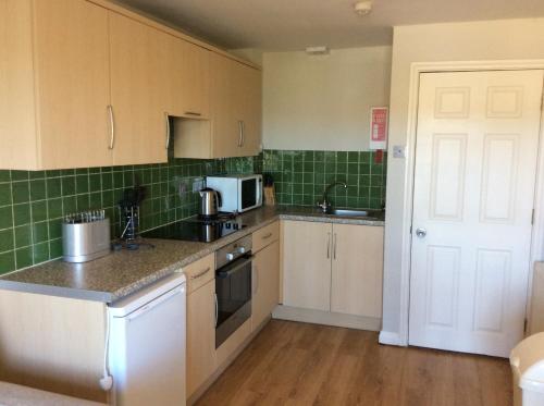 a kitchen with white cabinets and green tiles at Discovery Bay in St Ouen's