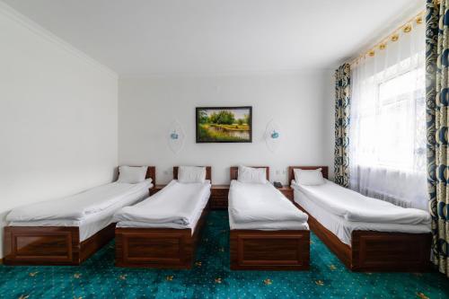 four beds in a room with a window at Qibla Tozabog in Khiva