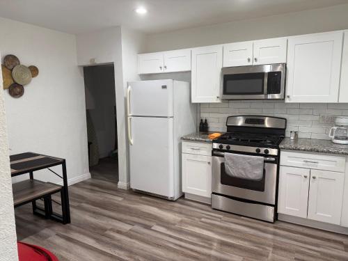 a kitchen with white cabinets and a stove and refrigerator at Las Vegas Great Location 2 Min to LV Strip in Las Vegas